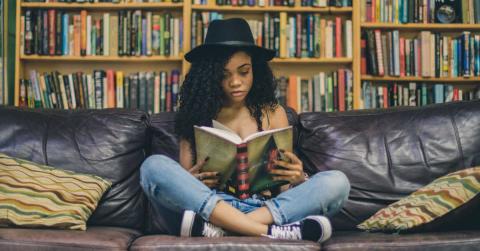 Teen girl sitting on sofa reading a book