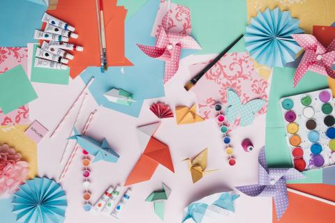 Various crafting supplies and origami animals spread out around the surface