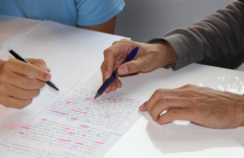 Hands with pens correcting a written paper.