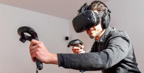 A teen boy in a virtual reality headset with controllers in each hand