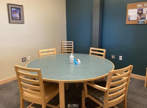 a round table with 4 chairs; 2 chairs along the wall