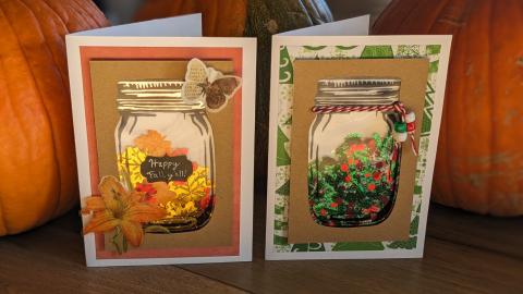 Two homemade cards in front of pumpkins, with see-through mason jar shapes filled with fun confetti and decorations.