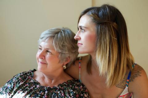 A photo of an older woman leaning into the embrace of a younger woman.