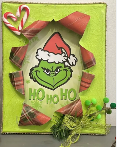 A green busted canvas with a picture of the Grinch. Candy canes and Christmas wrapping also adorn the canvas.