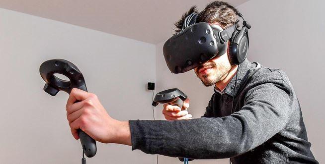 A teen boy in a virtual reality headset with controllers in each hand.