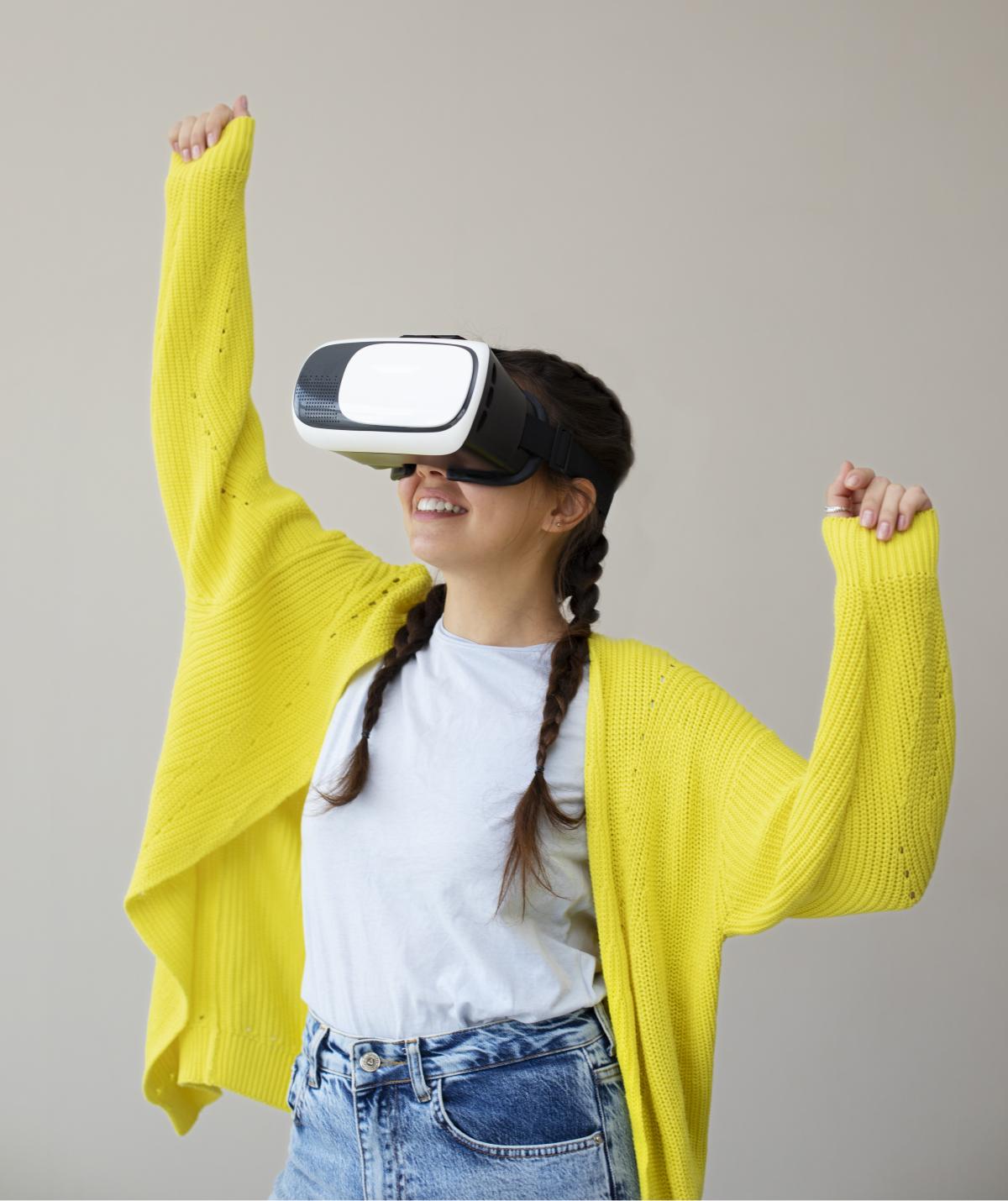Teenage girl with arms in the air and wearing a virtual reality headset