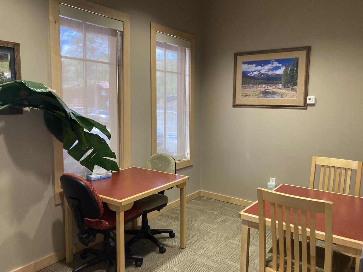 A small room with 2 rectangular tables; each table has 2 chairs