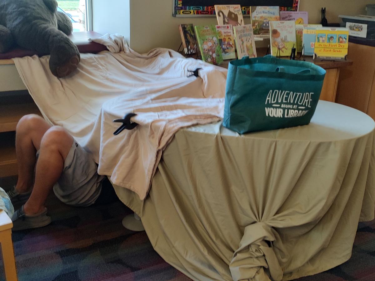 Blankets over tables with bookbag on top of the table.