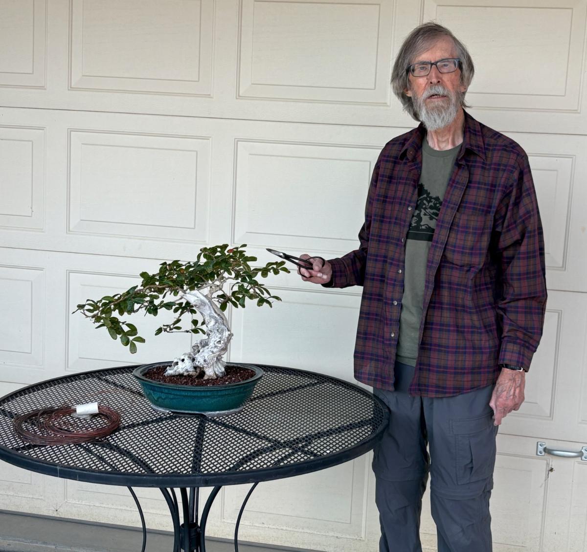 Man standing with bonsai tree.