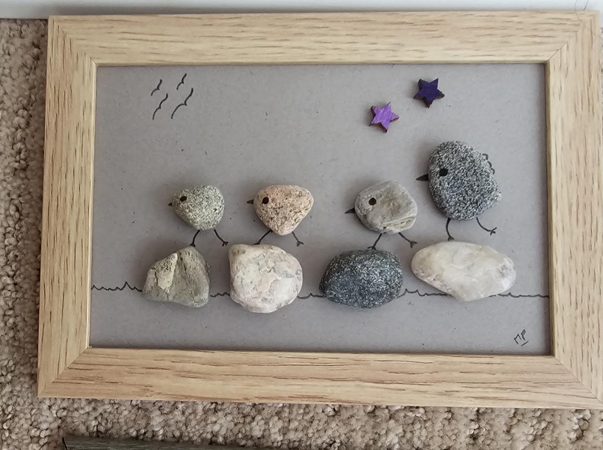 Birds made from rocks sitting on a rock branch.